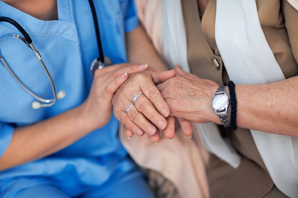 WLC nurse and resident holding hands